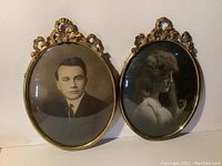 Front view of both oval parabolic convex picture frames with vintage black and white photos of a man and a woman. Shows overall condition and decorative tops.