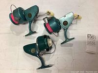 Three teal Penn Spinfisher reels laid flat