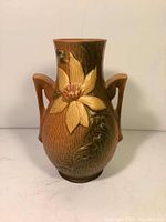Front view of Roseville vase showing large yellow flower and dual handles