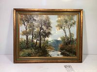 Frontal view of the framed oil on canvas painting showing the outdoor landscape scene with the gold frame.