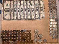 Top down view showing multiple rows of wheat pennies and circulated US coins alongside two rows of mixed silver and regular coins on cardboard.