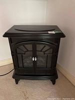 Front view of black Muskoka electric fireplace, showing the two window-paned doors and control dials on top right corner.