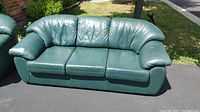 Front view of the green leather 3-seater sofa showing three cushioned seats and padded armrests.