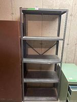Front view of metal utility shelf showing five shelves with visible dents and wear.