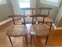 Front view showing all four teak chairs with leaf-patterned upholstery