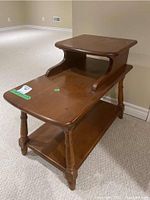 Photo showing angled front view of Vilas wood end table with upper raised shelf, curved supports, and lower shelf on turned legs, surface scratches visible.