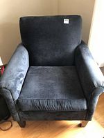 Front view of navy blue upholstered armchair with padded armrests and wooden legs, showing overall condition.