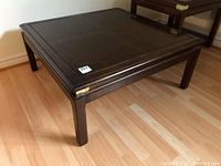 Wooden square coffee table with dark finish and slight signs of wear.