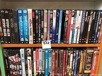 Photo showing multiple DVDs arranged on shelves with titles including NYPD Blue, Rocky, Remington Steele, Mad City, Frantic, etc.