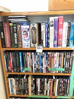 Photo showing shelves with DVDs and VHS tapes including titles like Blazing Saddles, Medic 2, Indy, and Locke.