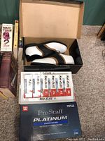 Top view of golf shoes in box, with boxes of Wilson and Top Flite golf balls beside