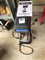 Top front view of the King Canada bench drill press showing the drill press head with logo and instruction manual on top.