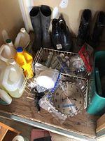 Photo showing boots, multiple plastic jugs of liquids, Mastercraft clock, and zip ties on a wooden surface.
