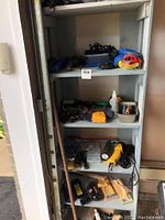 Shelving unit with multiple shelves holding various hand tools including flashlights, measuring tapes, soldering tool, markers, chalk lines, sanders, and other miscellaneous items.
