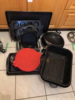 Photo of various kitchen bakeware including muffin tins, roasting pan, cookie sheet, cooling racks, and frying pan.