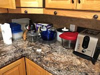 Countertop display of all kitchen items including toaster, electric chopper, mixing bowl, storage containers, rolling pin, cutting board, and kitchen scale box