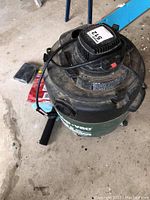 Top angled view showing the handle, power cord wrapped around the motor housing, and the general used condition of the ShopVac.