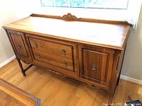 Front right three-quarter view of sideboard showing drawers, cupboard doors, decorative backsplash, turned legs