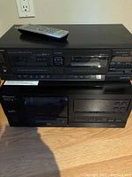 Top photo showing Technics RS-T22 double cassette deck on top of Pioneer PD-F407 CD player with remote placed on top of cassette deck.