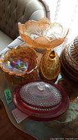 Large amber carnival glass footed bowl and various covered glass dishes including iridescent candy dish and red covered oval dish