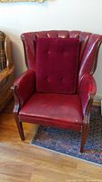 Full front view of the red leather wingback chair with the red tufted cushion on the seat.