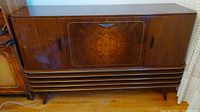 Front view of the Art Deco wooden console stereo showing symmetrical wood veneer design, side cabinet doors and base grille detail.
