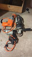 Photo showing the Mastercraft angle grinder alongside two corded electric drills on a concrete floor.