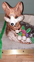 Close-up image of the ceramic planter showing the adult fox head and baby fox figure along with some flowers and mushrooms details on the side.