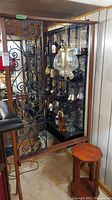 Full view of mid-century modern wooden divider with wrought iron decorative panel and glass shelving containing liquor bottles, and swag lamp hanging in front.