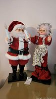 Front view of Mr and Mrs Claus figurines standing side by side on display surface