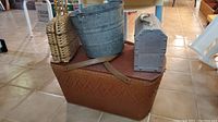 Woven picnic basket with leather straps, galvanized metal pail, and small woven bag