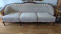 Front view of vintage 3-seater sofa with button-tufted backrest and three seat cushions.
