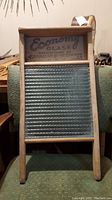 Full frontal view of wooden framed washboard showing glass scrubbing panel and top branding.