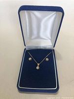 Frontal view of necklace with pendant and earrings displayed in blue presentation box