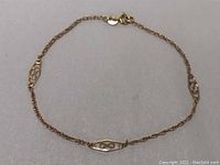 Full view of a 7-inch gold bracelet with decorative geometric cut-out links and a spring ring clasp.