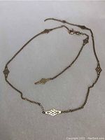 Full view of 10k gold chain with ornamental cutout elements spaced on chain laid out flat.