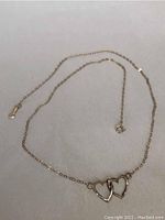 16 inch delicate gold chain necklace with interlocking open heart pendants shown fully extended on a flat surface.