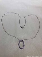 Full view of 18 inch fine chain gold necklace with oval gemstone pendant on light background