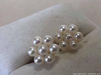 Close-up photo of front view of gold earrings showing clusters of round white pearls