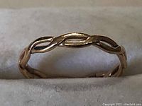 Close-up side view of the twisted band 10k gold ring showing the intertwined design details.