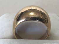 Front view of dome-shaped gold ring on display holder