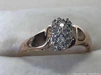 Front view of ring showing oval diamond cluster on yellow gold band