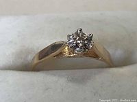 Front view of a ladies gold ring with a cluster of small diamonds set in a floral arrangement on a tapered yellow gold band.