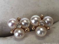 Front view showing both earrings with three pearls and central diamond on gold settings