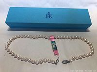 Pearl necklace with Birks box and ribbon tag laid out flat