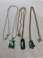Overview of three jade pendants with their chains laid out side by side