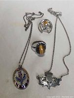 Full lot view showing all four jewelry pieces: two necklaces, a ring, and a brooch on a plain background.