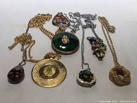 7 vintage pendants with assorted chains displayed on white background