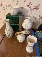 Overview of five porcelain items including boxed bowl, candle stand base and shade, and three vases on wood table