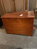 Wooden storage chest with closed lid showing front, keyhole and wood finish.